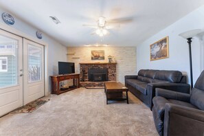Ein Wohnzimmer mit Kamin, Fernseher, Sofa und Couchtisch.