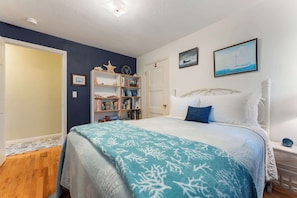 Un dormitorio con una cama, una estantería, una puerta y un cuadro en la pared.