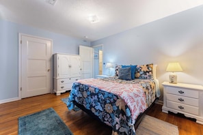 A bedroom with a bed, nightstands, a dresser, and a door. - Pet-friendly - Walk to the beach, explore downtown Newport, and unwind in this cozy coastal getaway just steps from the Oregon coast (Newport)