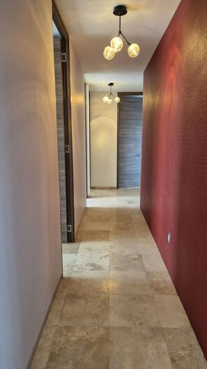Un couloir doté d’un luminaire moderne, d’une porte et d’un mur à texture.