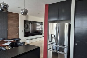 A modern kitchen with a stainless steel refrigerator, a built-in oven, and a dining area with a table and chairs. - Depa moderno piso7- Recamaras -Elevador+2 cajones (Zapopan)