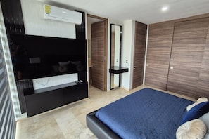 Quarto com cama, televisão integrada, guarda-roupa e espelho.