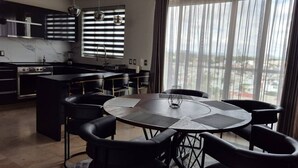A modern kitchen with a central island, black chairs, and a round table. - Depa moderno piso7- Recamaras -Elevador+2 cajones (Zapopan)