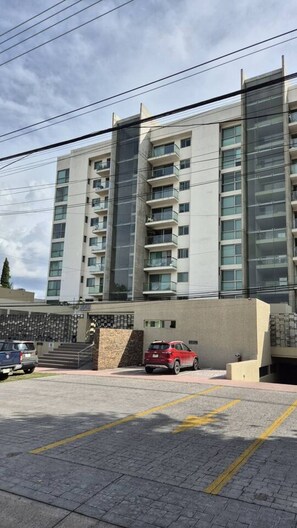 A multi-story residential building with a parking area in front. - Depa moderno piso7- Recamaras -Elevador+2 cajones (Zapopan)