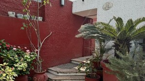 A courtyard with potted plants, a staircase, and a building with a red wall and a white facade. - Casa Andares 3 REC Y 3 BANOS (Zapopan)