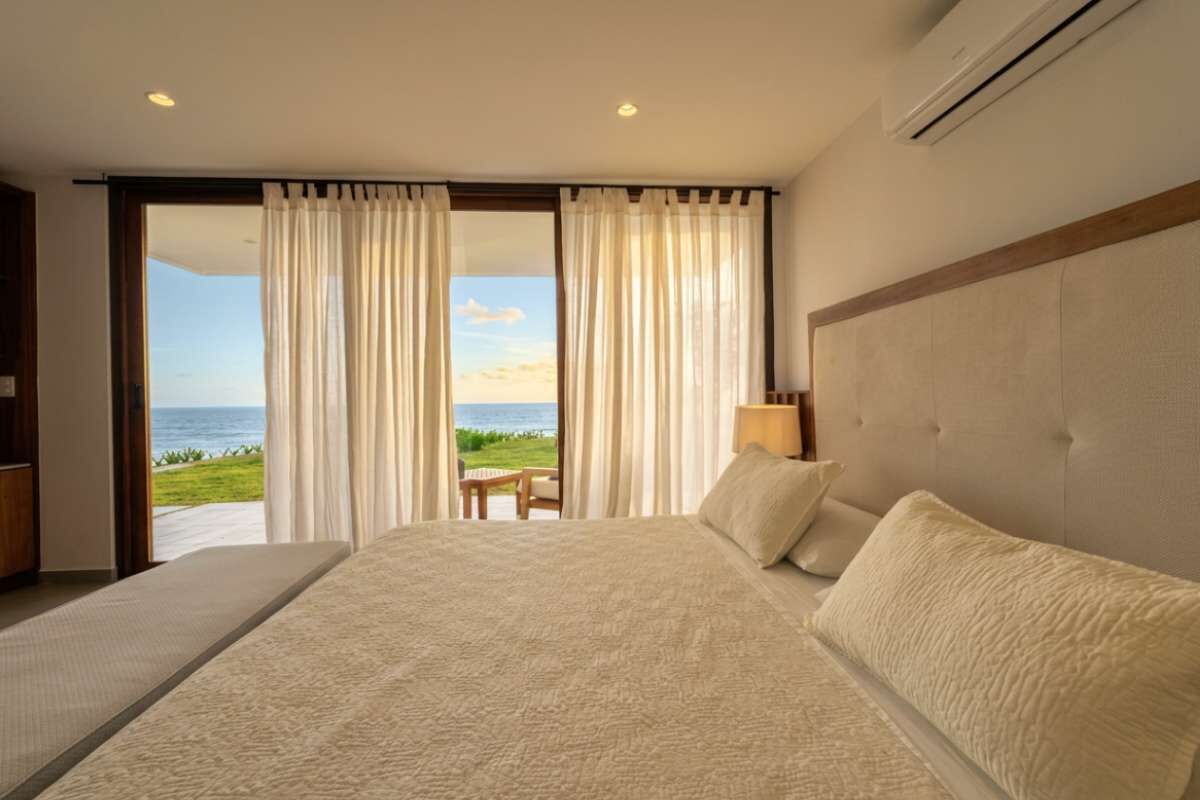 Una camera d'albergo con un letto grande, vista sul mare e una porta finestra.