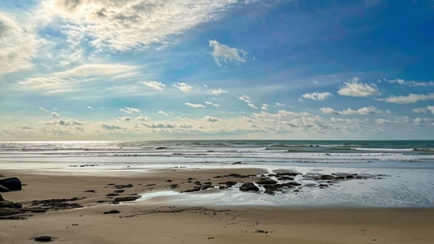 Een strand met heldere lucht en golven.