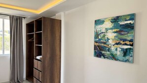 Ein Zimmer mit eingebautem Holzschrank, einem großen abstrakten Gemälde an der Wand und einem Fenster mit Vorhängen.