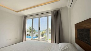 Ein Hotelzimmer mit einem großen Bett, Blick auf den Pool und einer Schiebetür.