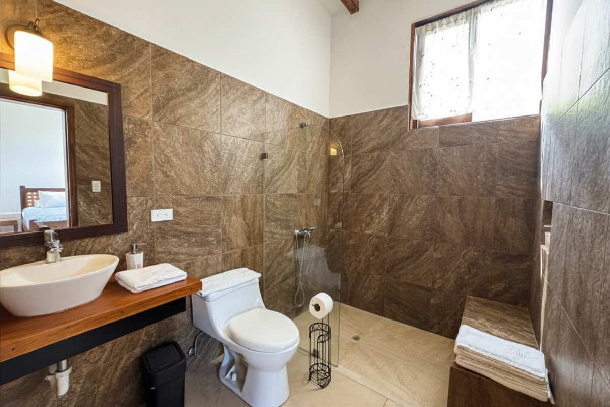 A bathroom with a large sink, toilet, and shower.