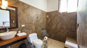 A bathroom with a large sink, toilet, and shower.