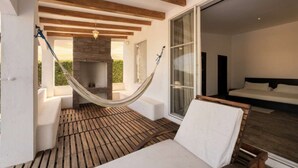 A room with a hammock, a fireplace, a bed, and a view through a glass door. - Beachfront | Pool With Views | Family & Friends (Camarones)
