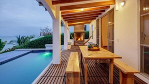 A wooden deck with a pool, a hammock, and a table with a basket of fruits. - Beachfront | Pool With Views | Family & Friends (Camarones)
