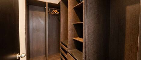 A walk-in closet with dark wood shelving and a hanging rack.