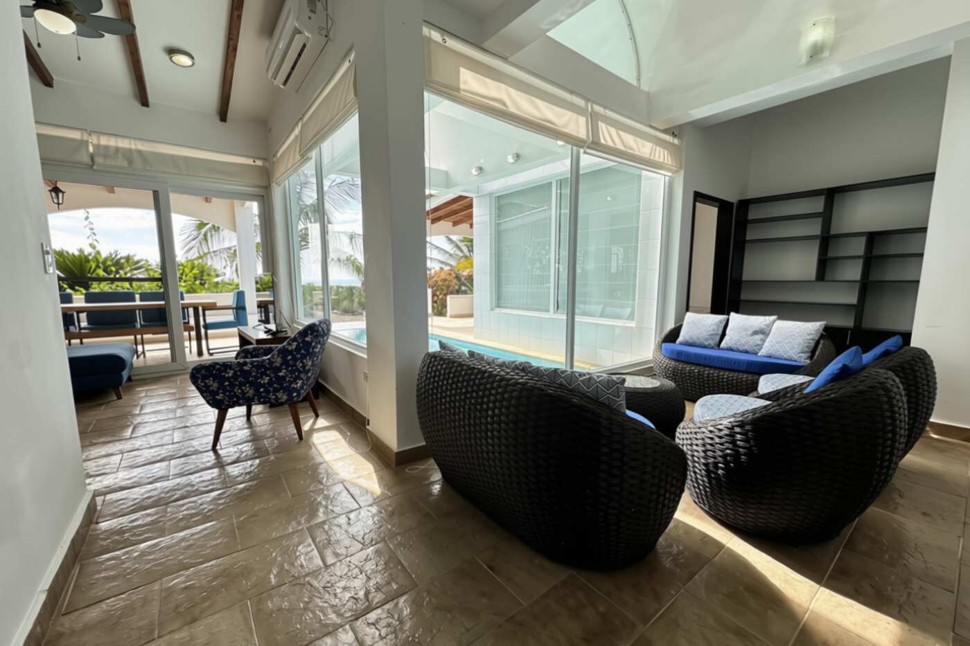 Un amplio espacio interior con un ventanal grande, una piscina y zona de estar exterior.
