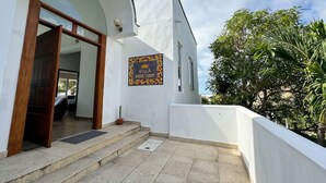 Ein Gebäude mit weißer Fassade, einer gefliesten Eingangspforte und einem Schild mit der Aufschrift 'Villa'.
