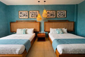 A room with two beds, each with a wooden headboard and white bedding. There are two wall-mounted light fixtures and three framed artworks above the beds.