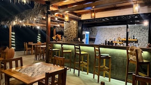 Eine Bar mit Holzbeschaffenheit, einer Steinwand und hängenden Lampen.