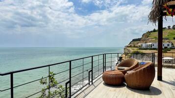 A coastal balcony with wicker furniture and a view of the sea.