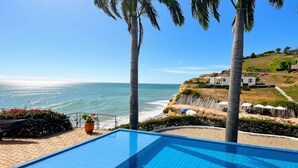 En swimmingpool med utsikt över havet och en sluttning med byggnader.