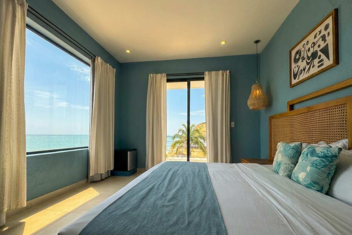 Ein Schlafzimmer mit einem großen Bett, Meerblick und einer Deckenleuchte.