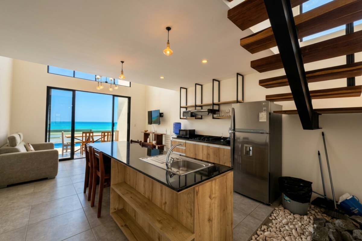 A modern kitchen with a central island, stainless steel appliances, and a view to the outside.