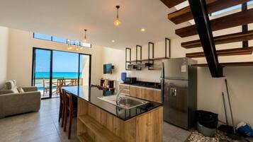 A modern kitchen with a central island, stainless steel appliances, and a view to the outside.