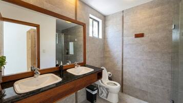 Une salle de bain moderne avec deux lavabos, des toilettes et un espace douche.