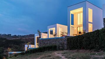 Una casa moderna de varios pisos con amplios ventanales y un muro de piedra en la base.