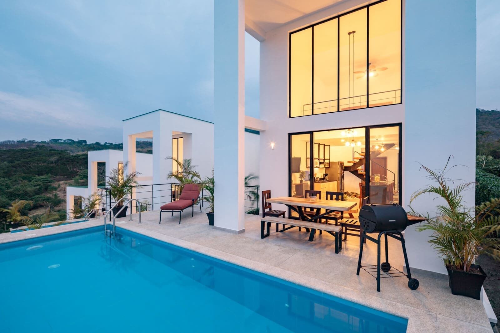 Una casa moderna con piscina, mobiliario de exterior y vistas al paisaje.
