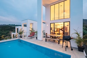 Une maison moderne dotée d’une piscine, d’un espace extérieur aménagé et offrant une vue sur le paysage.