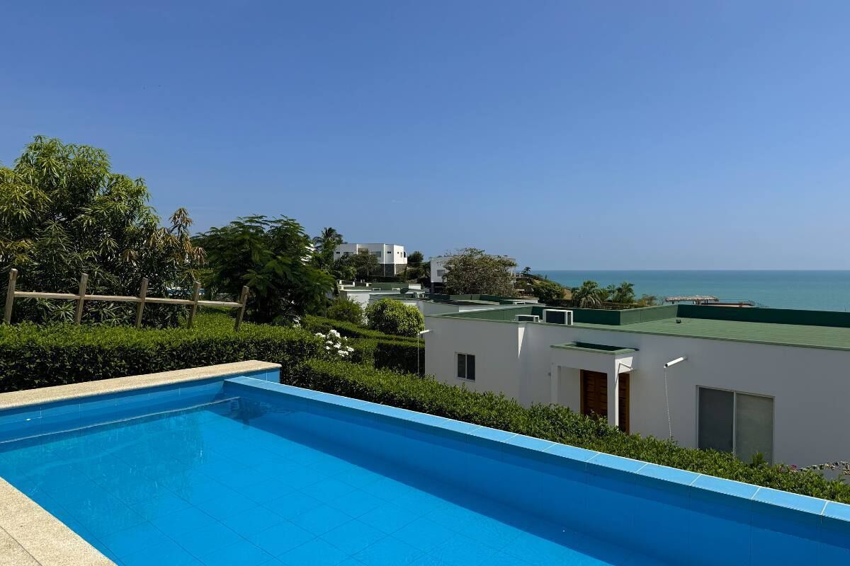 A swimming pool with a view of the sea and buildings in the background.
