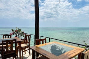 A wooden table and chairs on a balcony with a view of the ocean.