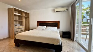 Een slaapkamer met een bed, een kledingkast, een airconditioning en een schuifdeur naar buiten.