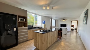 Een moderne keuken met een centraal eiland, een zwarte koelkast en een magnetron aan de linkerkant.