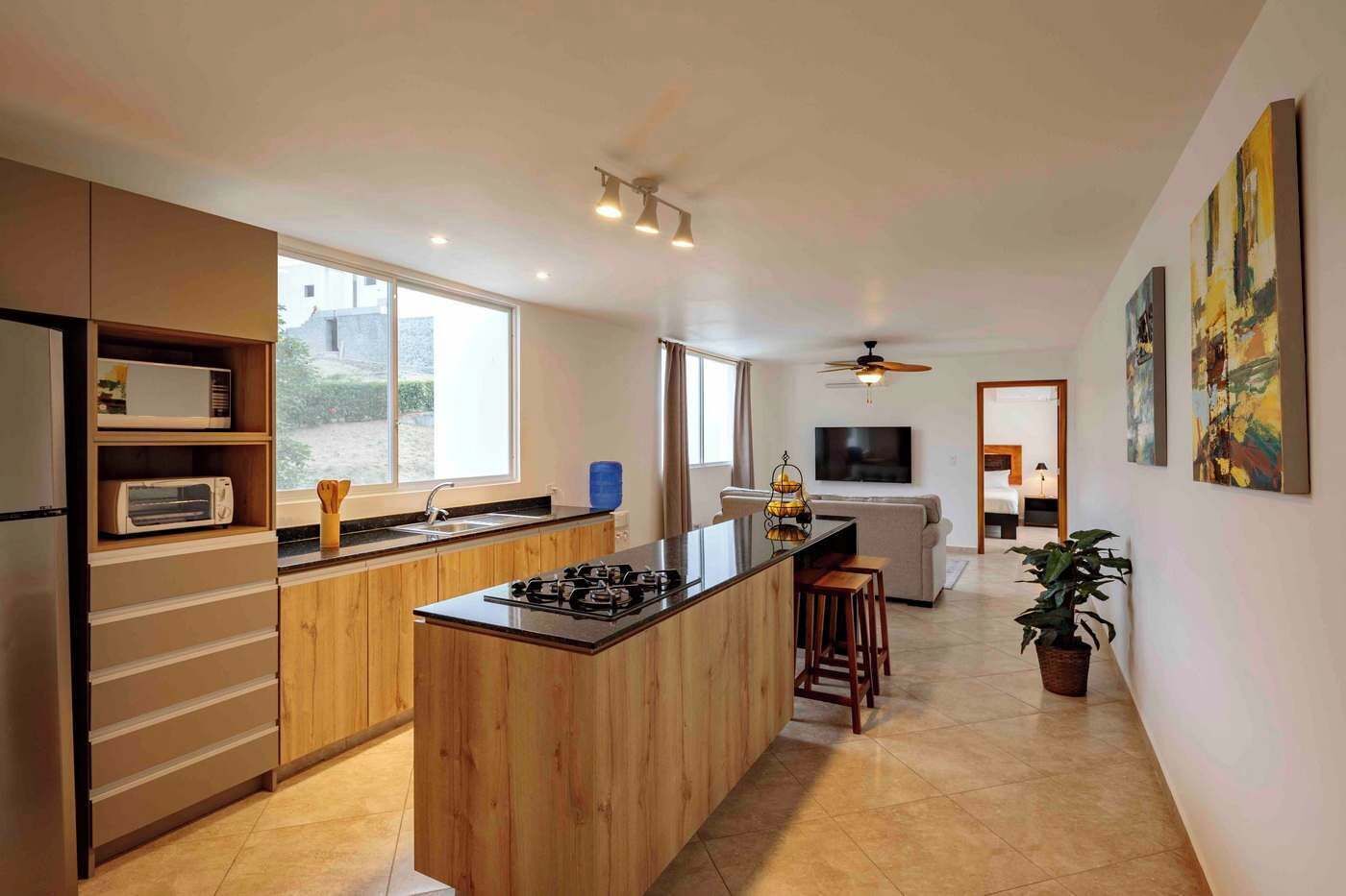 Eine moderne Küche mit Kochinsel, integrierten Geräten und einer Essecke mit Sofa und Fernseher.