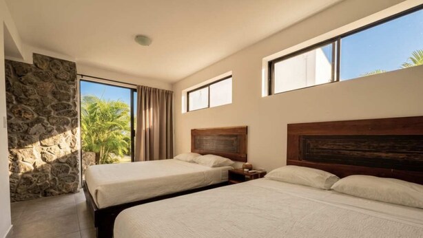 A hotel room with two beds, a stone wall, and a view of palm trees. - Oceanfront Villa | Private Pool | Jama Campay (Camarones)