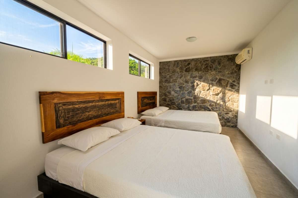 Ein Schlafzimmer mit zwei Betten, einer Steinsäule und großen Fenstern.