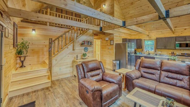 Ein Holzinnenraum mit Treppe, Ledersofas, einer Küchenzeile und einem Esstisch.