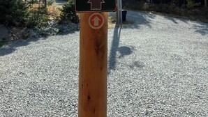 Wanderwegweiser mit Pfeilen auf einem Holzpfosten.