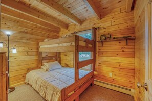 Ein Zimmer mit einem Holzbett mit Etagen, einem Fenster, einem Regal mit einer Uhr und einer Lampe.