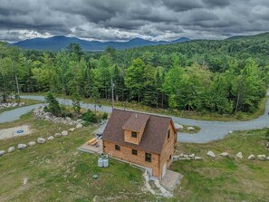 A cabin with a sloped roof, surrounded by a forest and a winding road. - The Havana Cabana | Log Cabin Escape (Bethlehem)