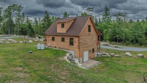 Eine Blockhütte mit geneigtem Dach, einer Veranda und einer kleinen Terrasse.