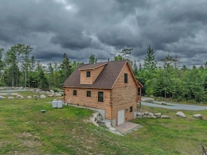 Eine Blockhütte mit geneigtem Dach, einer Veranda und einer kleinen Terrasse.
