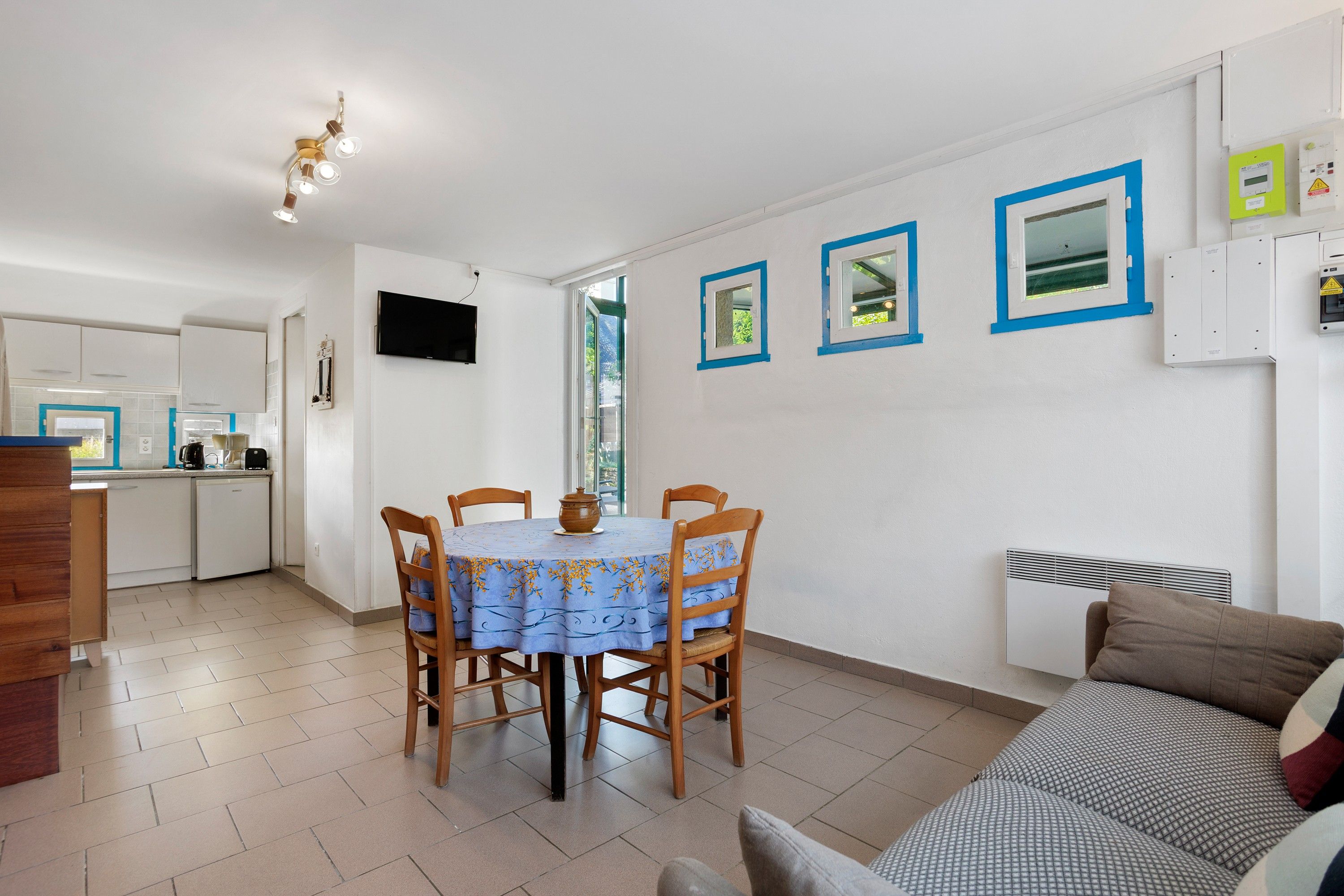 A compact living space with a dining area, kitchenette, and a sofa.