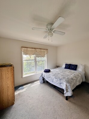 A bedroom with a bed, a ceiling fan, a window with curtains, and a wooden cabinet. - 2 blocks to Roger Wheeler Beach 4-bedroom house perfect for your Summer getaway! (Narragansett)
