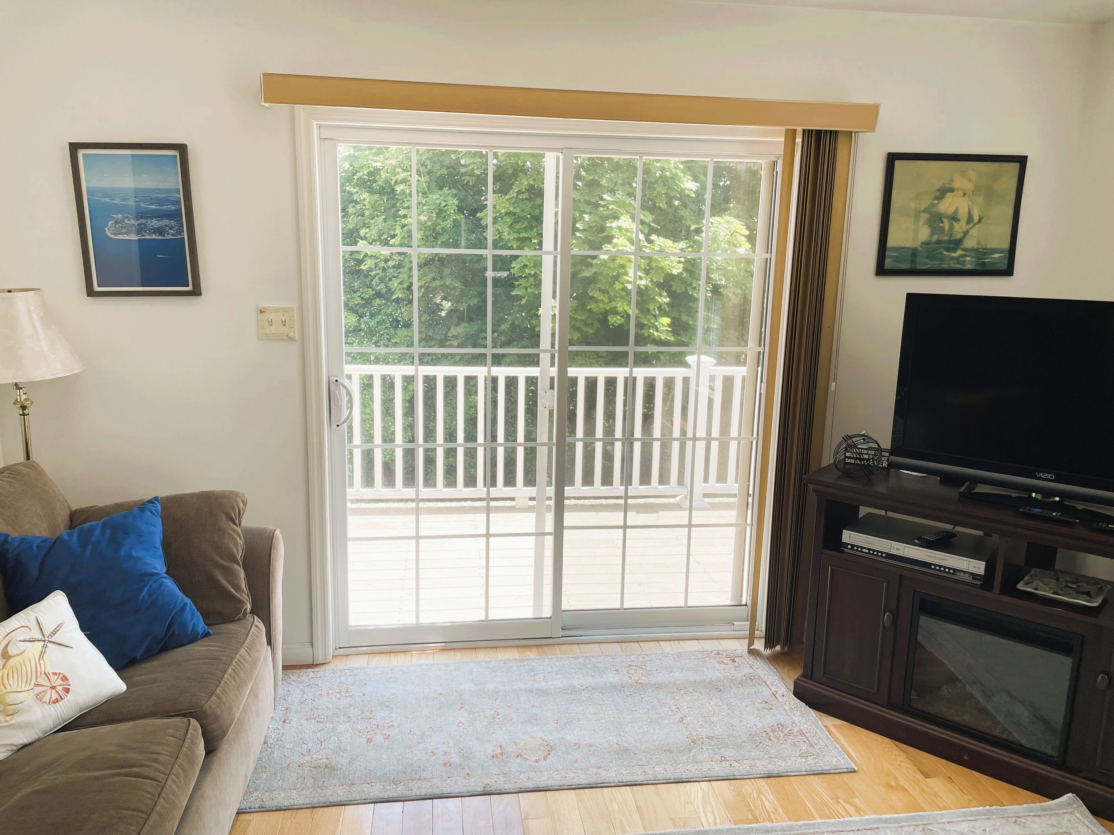 A living room with a sofa, a television, a fireplace, and a sliding glass door leading to a balcony.