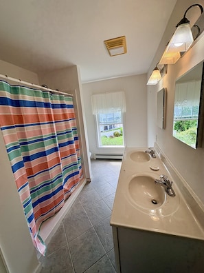 A bathroom with a shower curtain, a window, a sink, and a mirror. - 2 blocks to Roger Wheeler Beach 4-bedroom house perfect for your Summer getaway! (Narragansett)