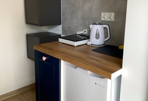 A compact kitchen area with a built-in coffee maker, a small appliance, and a power outlet on the wall. - Room for 4 People With Kitchenette (Mielno)
