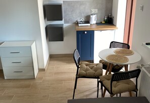 A compact kitchen with a built-in stove, a small dining area with two chairs and a table, and a white cabinet with drawers. - Room for 4 People With Kitchenette (Mielno)